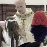 Il cardinale Bertone dà l'Eucarestia ai ragazzi della Prima Comunione